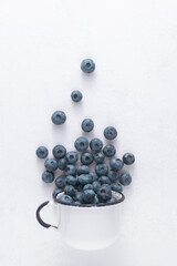 Delicious blueberries in a white mug on a white background.