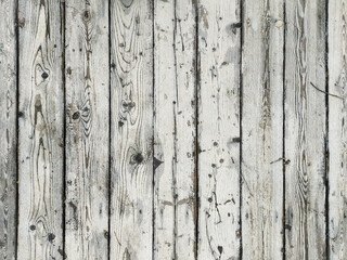 Fototapeta premium Old white wood plank texture, arranged vertically, light natural background. The texture of the wood is visible through the cracked and worn layer of white paint.