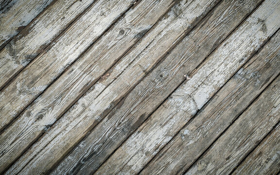Old white wood plank texture, angled, light natural background. The texture of the wood is visible through the cracked and worn layer of white paint.