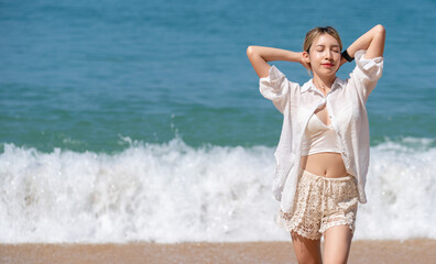 Happy young woman relax on the beach, arms raised up to sky.