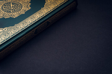 Holy Al Quran with written arabic calligraphy meaning of Al Quran on black background. Copy space...
