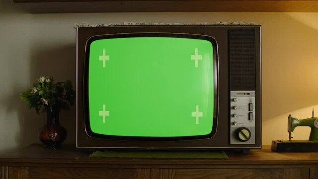 Old Retro Wooden TV in a vintage ambient with a green screen on it.