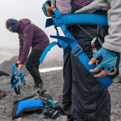Two Mountain climbers (girls) put on harness preparing to ascent.