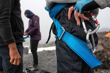 Two mountain climbers (girls) are preparing to ascent under control of guide (man).
