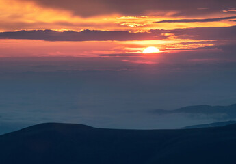 Fototapeta na wymiar Surise in the mountains. Sun rising up above clouds.