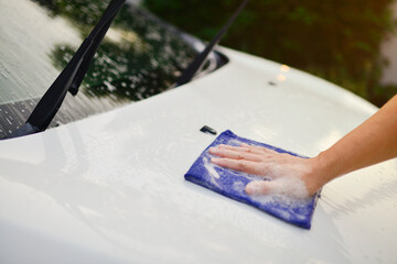 Man cleaning car with microfiber cloth at car wash