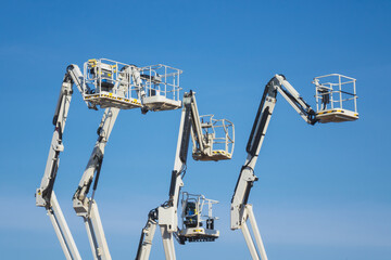 Articulated boom lift. Aerial platform lift. Telescopic boom lift against blue sky. Cherry pickers