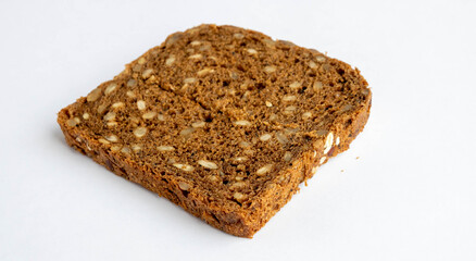 Slice of whole-grain dark bread, isolated on a white background close-up