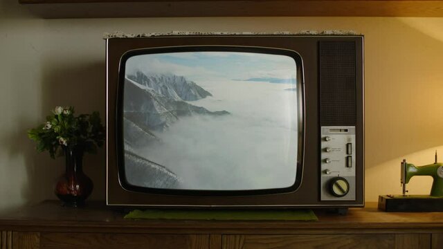 An old analog TV showing a Mountains covered with the snow on the screen.