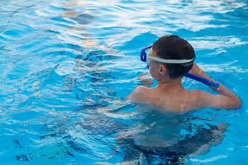 Boy swims in the pool in a mask and snorkel in the summer