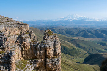 Fototapeta na wymiar View of Bermamyt plateau rocks and mount Elbrus on sunny day. Karachay-Cherkessia, Caucasus, Russia.