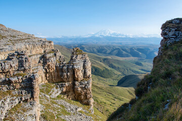 Fototapeta na wymiar View of Bermamyt plateau rocks and mount Elbrus on sunny day. Karachay-Cherkessia, Caucasus, Russia.