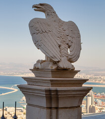 In the Bahai gardens, a marble eagle gargoyle statue is looking at Haifa's horizon. Beautiful sculpture of eagle on terrace at the Hanging Gardens of Haifa, Israel.