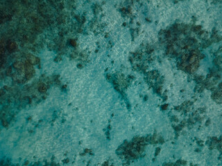 Clear green ocean surface background with reef at the bottom aerial view