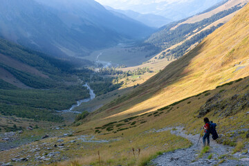 Fototapeta na wymiar A hiker (girl) climb up Sophia Sedlo pass in Sophia river valley (Arkhyz region). Karachay-Cherkessia, Caucasus, Russia.