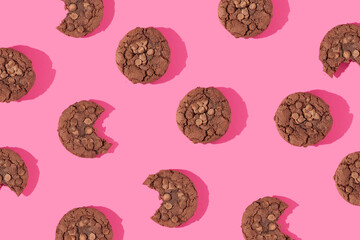 Creative pattern made with chocolate chip cookies on bright bold pink background. Happy sweet...