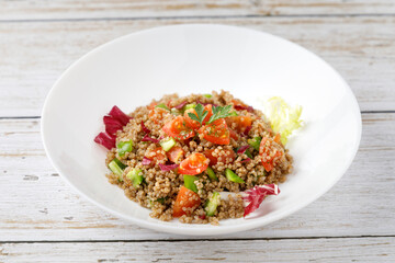 Healthy rustic quinoa salad with vegetables on a white wood table
