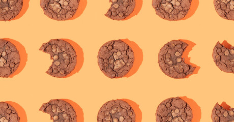 Creative pattern or frame made with chocolate chip cookies on bright bold orange background. Happy sweet fun life idea. Trendy food or dessert concept. Spring or summer layout.