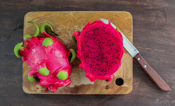 Dragon fruit on a wooden board (Pitaya). Dragon fruit on wooden board with a knife. Simple image isolated. Top view.
