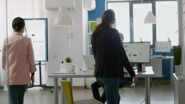 Coworkers wearing face masks greeting each other with elbow while working in new normal company office during coronavirus lockdown. Team respecting social distancing to prevent infection with virus
