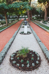Gravel pathway in the Bahai Gardens that include areas with cactuses, yuccas and agaves, growing in separated plant beds. Haifa, Israel.