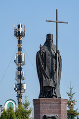 Father bless 4G (and 5G). View of St Pitirim of Tambov statue and communication tower on sunny day. Tambov, Tambov Oblast, Russia.