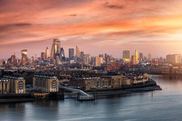 Fototapeta na wymiar The urban skyline of London, United Kingdom, along the Thames river to the City during a colorful sunrise with orange and pink cloudscape 