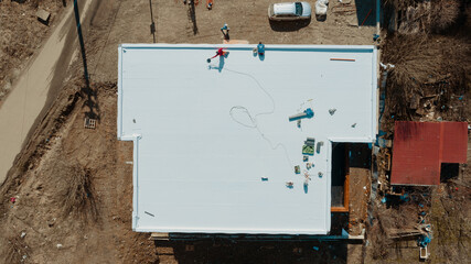 Aerial view of an apartment building with flat roof in construction, ballasted system with...