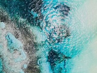 Blue Ocean Waves and White Foam with Grey Rocks Below the Water Aerial Drone Shot