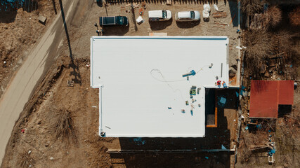 Aerial view of an apartment building with flat roof in construction, ballasted system with...