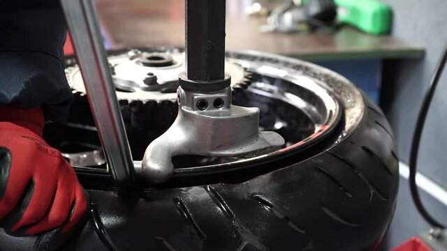 tire fitter puts a tire on a car disc using a special tool. car service. car repair shop.