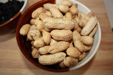 Assortment of raisins and nuts in clay dishes with wooden table background. Organic produce.