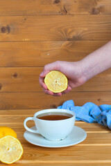 Man's hand squeezing half a lemon into a bowl.