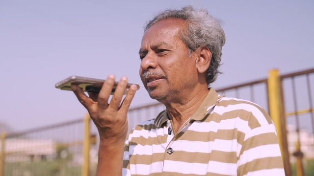 Senior man receiving call and speaking on phone speaker - concept of old people lifestyle, communication and technology.