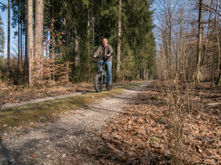 Obraz premium Young man rides modern E-bike through the forest