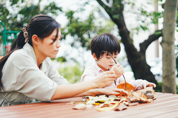 葉っぱで遊ぶお母さんと息子