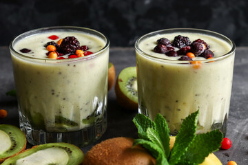 Yogurt with berry and kiwi in a glass. Fruit and berry smoothie. Milkshake with kiwi, raspberry, blueberry and banana Healthy food. Dark background. Copy space.