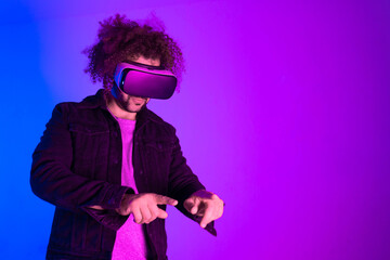 Hipster young man using virtual reality headset over blue purple background. Concept of hi tech and modern technology.