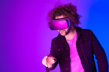 African american man is wearing virtual reality headsets. Neon light studio portrait. Virtual reality, simulation, game and future technology concept.
