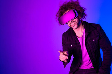 African american man long afro hair with vr glass, playing video games with virtual reality headset, trying to touch something with his hand. pink blue background