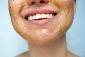 Fragment of a woman's face with a golden cosmetic mask. Beautiful female smile. Skin care concept. Real skin.