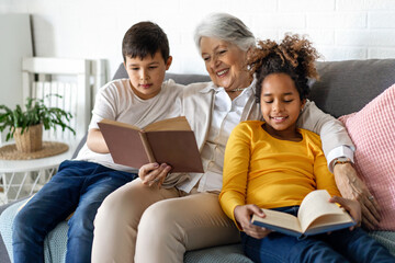 Multiethnic family. Grandparent teaching children to read for school