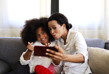 American kid girl smile portrait and selfie photo with mother at home.