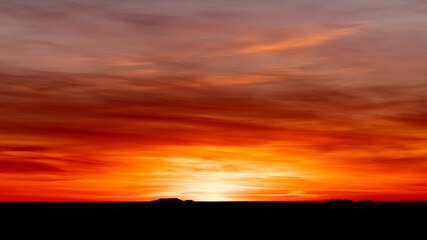 Fototapeta na wymiar Luminous sunset in bright orange and red with black silhouette coastline.Shot in Sweden, Scandinavia