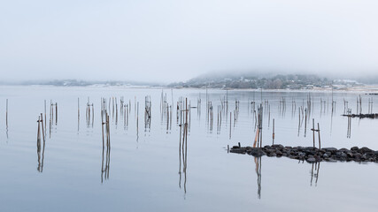 Misty winter morning on Swedish coastline. Bridges and reflections in water in early spring. Desolate feeling. Shot in Sweden, Scandinavia