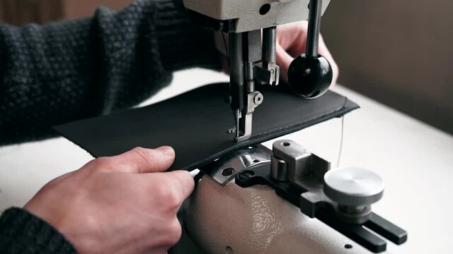 the master sews leather on a sewing machine