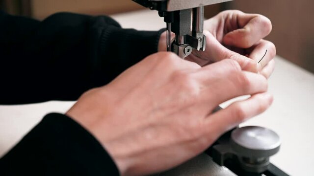 the master sews leather on a sewing machine