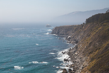 Fototapeta na wymiar Beautiful foggy coastline with cliffs and distant mountains in Big Sur, California