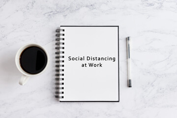 Notebook on desk written social distancing at work