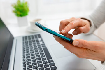 Woman's hands use mobile phone and laptop to shop online. Authentication in Internet banking on a smartphone and computer.